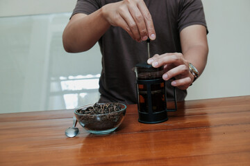 Close up a man hand brewing green tea in glass French press, on wooden table. Tea ceremony. Making tea.