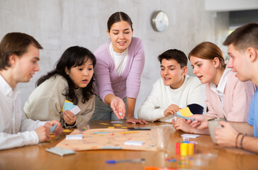 Group of happy young people playing board game