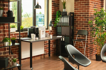 Coffee machine and water dispenser placed on wooden table in empty brick wall room. Modern office space with arranged cabinet, chairs and plant decorations, ready for calm therapy session.