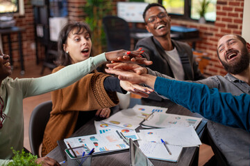 Male and female colleagues bonding through cheerful gesture, fostering positivity and teamwork in modern workspace. Professional business team smiling and celebrating new chapter for startup company.