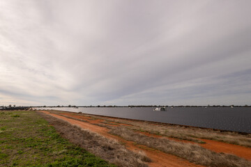 Threatening storm over a solar farm with vast numbers of panels, a service road and a number of collection stations to turn the solar output into energy for the grid in New South Wales, Australia.