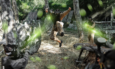 Group of people in full gear playing paintball on shooting range
