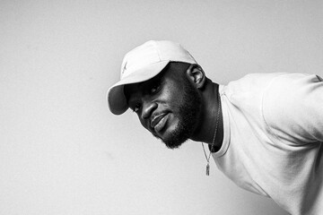 Stylish young black man in a cap smiling in a black and white portrait © Steed Ch.