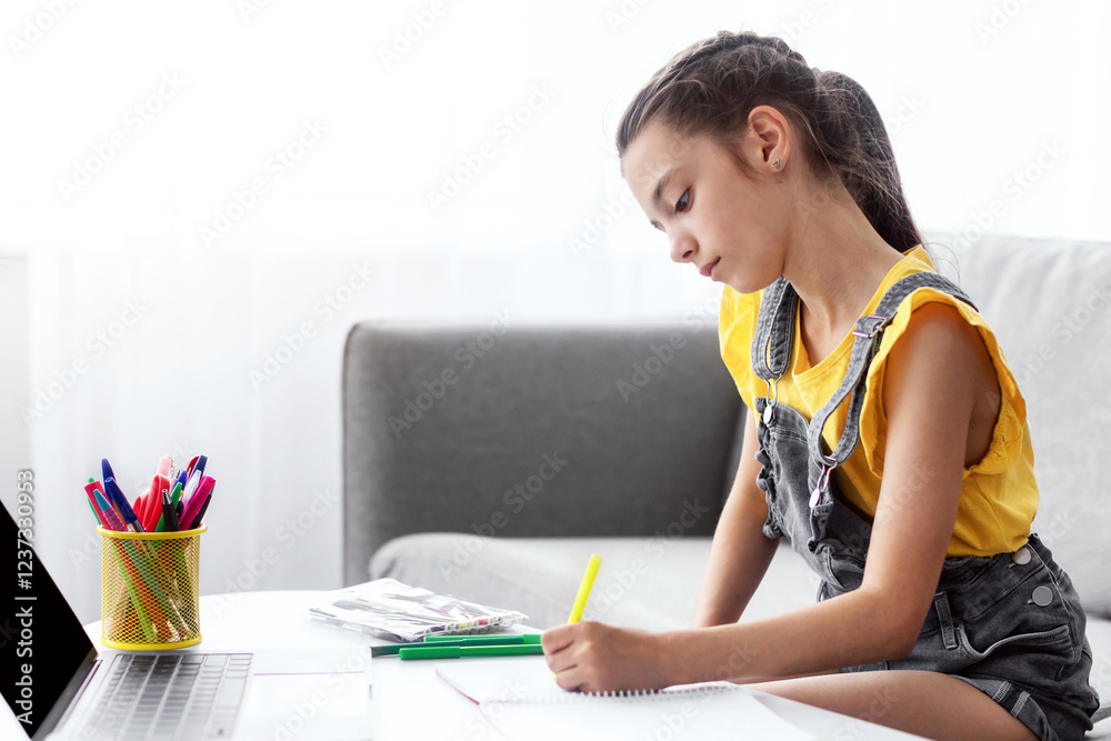 Poster Profile side view portrait of focused girl sitting on couch at table using laptop with blank empty screen, writing essay or making test, taking notes in textbook, doing homework, free copy space
