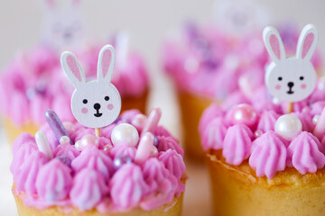 Easter Bunny Muffins with pink and purple cream.Easter cupcakes with white rabbits topiary with pink cream. Catholic and Orthodox holidays.Cute Bunny Decoration on Cake