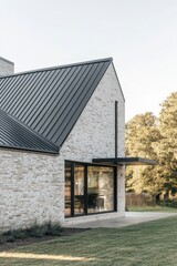 A contemporary brick residence featuring a sleek metal roof and expansive windows, beautifully set against a tranquil landscape under the bright daytime sky