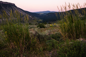 Mountain hills and green valley bathed in glow after sunset