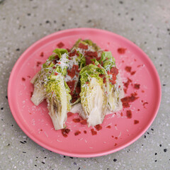 Cesar Salad. Top view of Romain Lettuce and bacon crisp topping for Cesar Salad served in a pink dish.