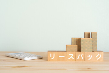 リースバックの文字が入ったブロック、電卓、マンションの模型