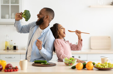 Kitchen Fun. Portrait of positive African American dad and his little daughter singing and dancing...