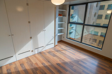 habitacion de departamento moderno con ventana y  closet , piso de melamina