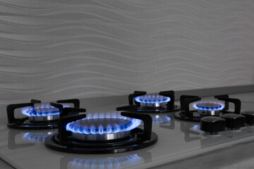 Modern gas cooktop with burning blue flames in kitchen