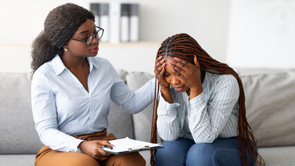 Upset black lady with nervous breakdown consulting psychologist, having session with counselor at...