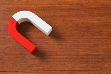 One horseshoe magnet on wooden background, top view. Space for text
