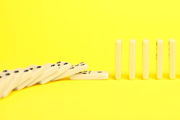 Domino effect. Tiles falling on yellow background