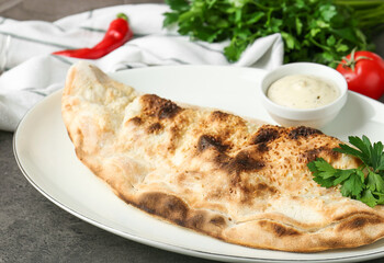 Delicious calzone served with sauce on grey table, closeup