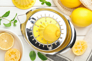 Plastic juicer and fresh lemons on white wooden table, flat lay