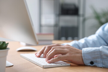 Man working on computer at wooden desk in office, closeup