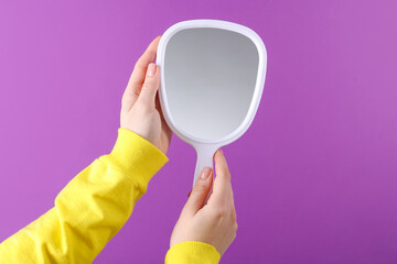 Woman holding handheld mirror on violet background, closeup © New Africa