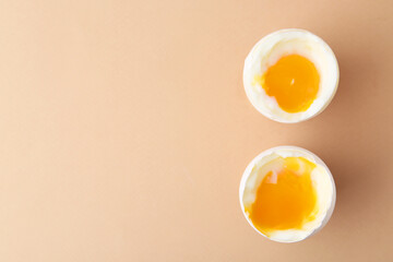 Soft boiled eggs in cups on beige background, top view. Space for text