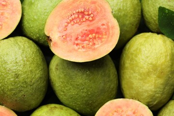 Fresh cut and whole guava fruits with water drops as background, top view