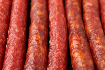 Different tasty smoked sausages as background, closeup