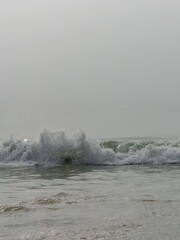 Low angle view of a wave breaking on the beach on an overcast day