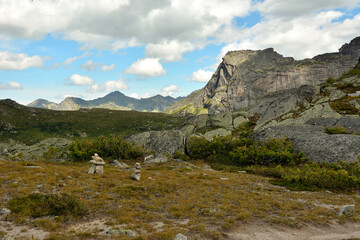 Ritual stone pyramids in a clearing in the lowland of a mountain valley at the foot of a mountain with a human profile.