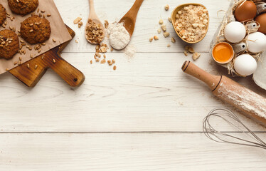 Cooking ingredients for oatmeal cookies background. Eggs, flour, spices and kitchen utensils on white wood table. Recipe or baking classes mockup, pastry making concept, top view, copy space