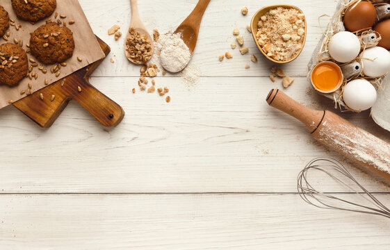 Cooking ingredients for oatmeal cookies background. Eggs, flour, spices and kitchen utensils on white wood table. Recipe or baking classes mockup, pastry making concept, top view, copy space