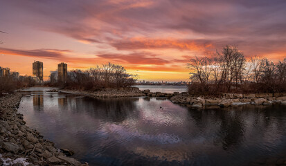 Fototapeta premium City skyline reflected in calm water at sunset.