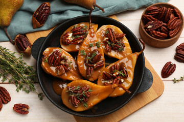 Delicious pears with caramel sauce, pecan nuts and thyme on wooden table, top view