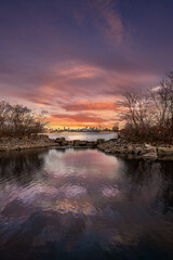 Obraz premium City skyline sunset reflected in calm water.