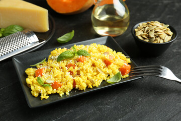 Delicious pumpkin risotto served on black table, closeup