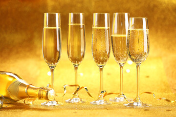 Champagne in glasses, bottle and streamers on golden background