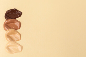 Samples of different foundations on beige background. Space for text