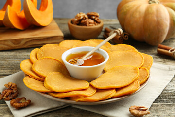 Tasty pumpkin pancakes, honey and walnuts on wooden table, closeup