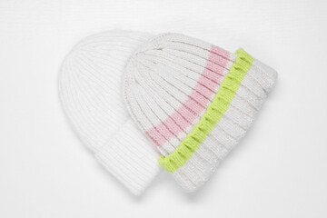 Stylish knitted hats on white background, top view