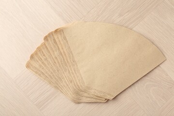 Paper coffee filters on light wooden table, top view
