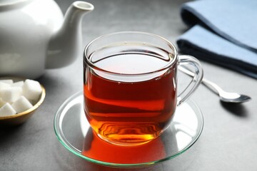 Refreshing black tea in cup on grey table, closeup