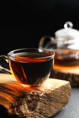 Aromatic black tea in cup on grey table, closeup