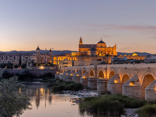 a dusk view of the ancient roman bridge and the mosque-cathedral of cordoba, spain
