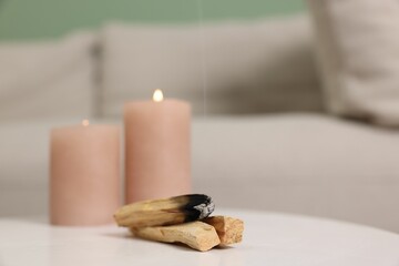 Palo santo sticks and burning candles on white table indoors, space for text