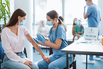 Obraz premium flu Vaccination Campaign. Young Lady Receiving Coronavirus Vaccine Injection In Arm Sitting With Doctor Or Nurse In Hospital. Corona Virus Population Immunization, Cure Medicine And Treatment