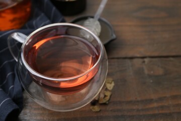 Delicious herbal tea and dry leaves on wooden table, closeup. Space for text