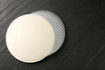 Edible rice paper sheets on dark textured table, top view. Space for text