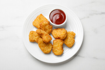 Delicious chicken nuggets and ketchup on white marble table, top view