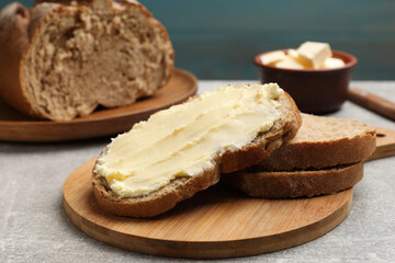 Fresh bread with butter on grey table, closeup