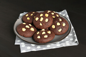 Delicious chocolate cookies with hazelnuts on black wooden table