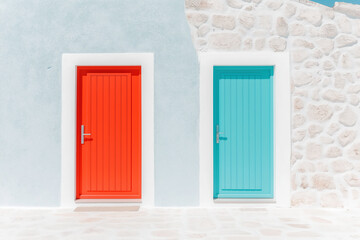 Two colorful doors on a white building, one red and one turquoise, in a minimalist style.